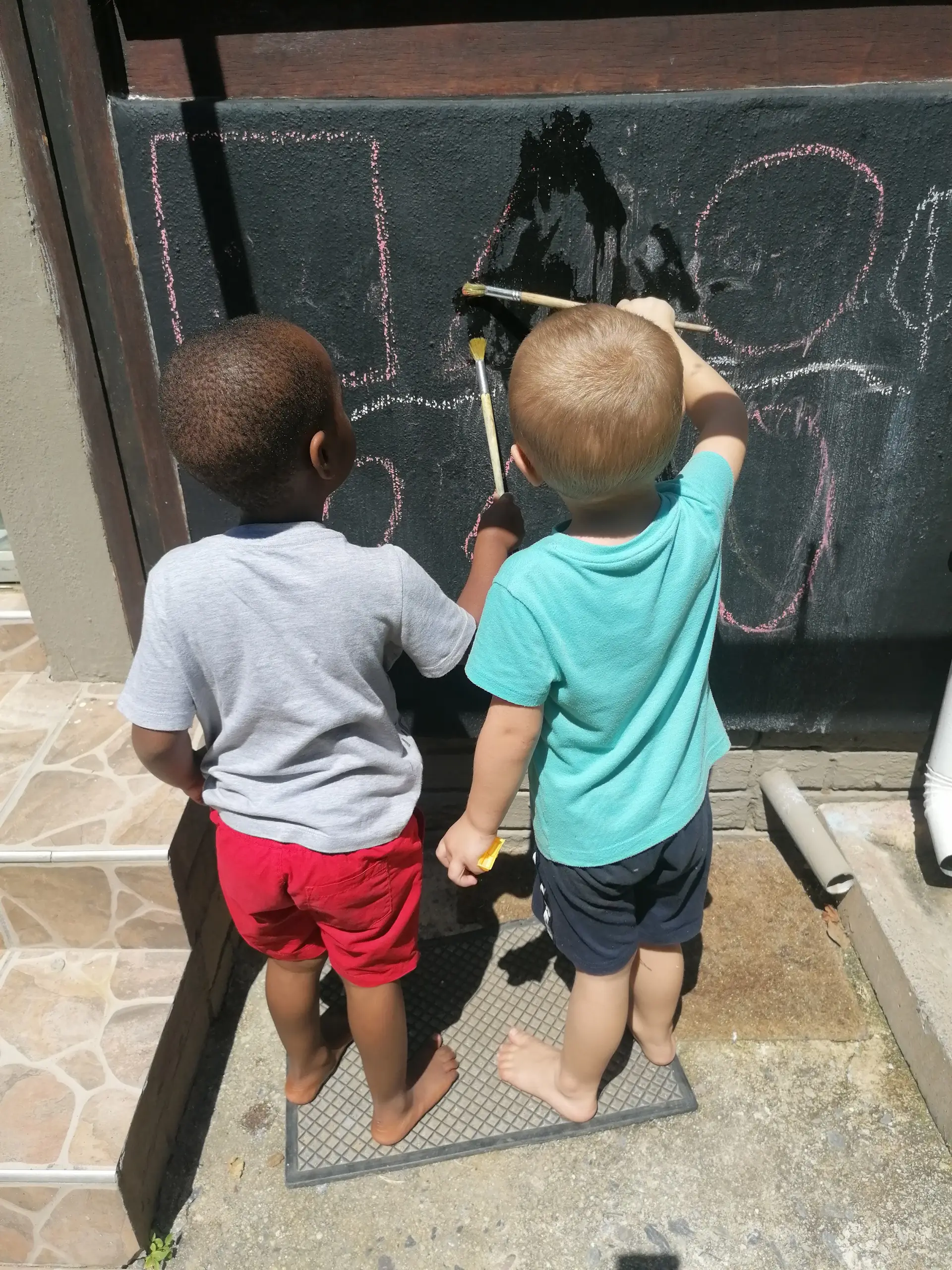 Two friends drawing on the chalk wall